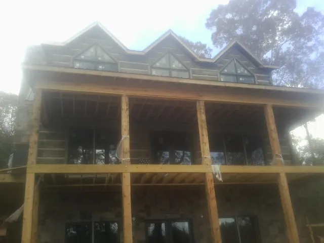 Dormers and porch framing on a large log home under construction — Roof Coating work by our crew in Ford