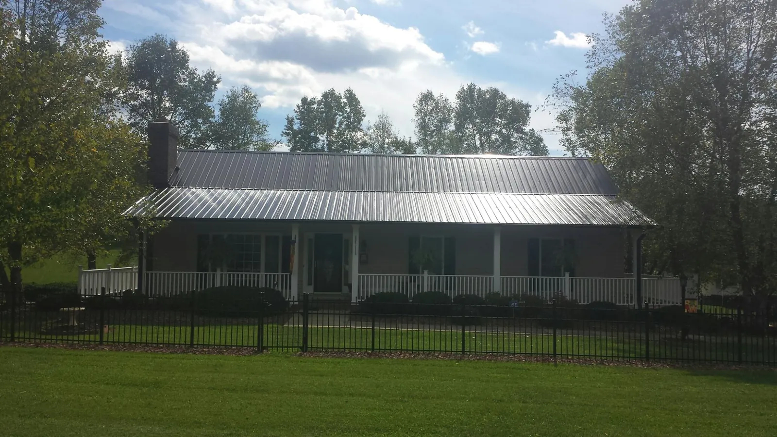 Gray metal roof on a brick ranch with a full width front porch — Gutter Guard Installation work by our crew in Ford