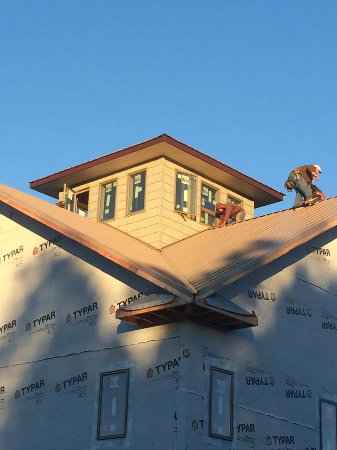 Roofers working around a rooftop cupola on a new metal roof at sunset — Roof Waterproofing in Ford by Roofing Brothers
